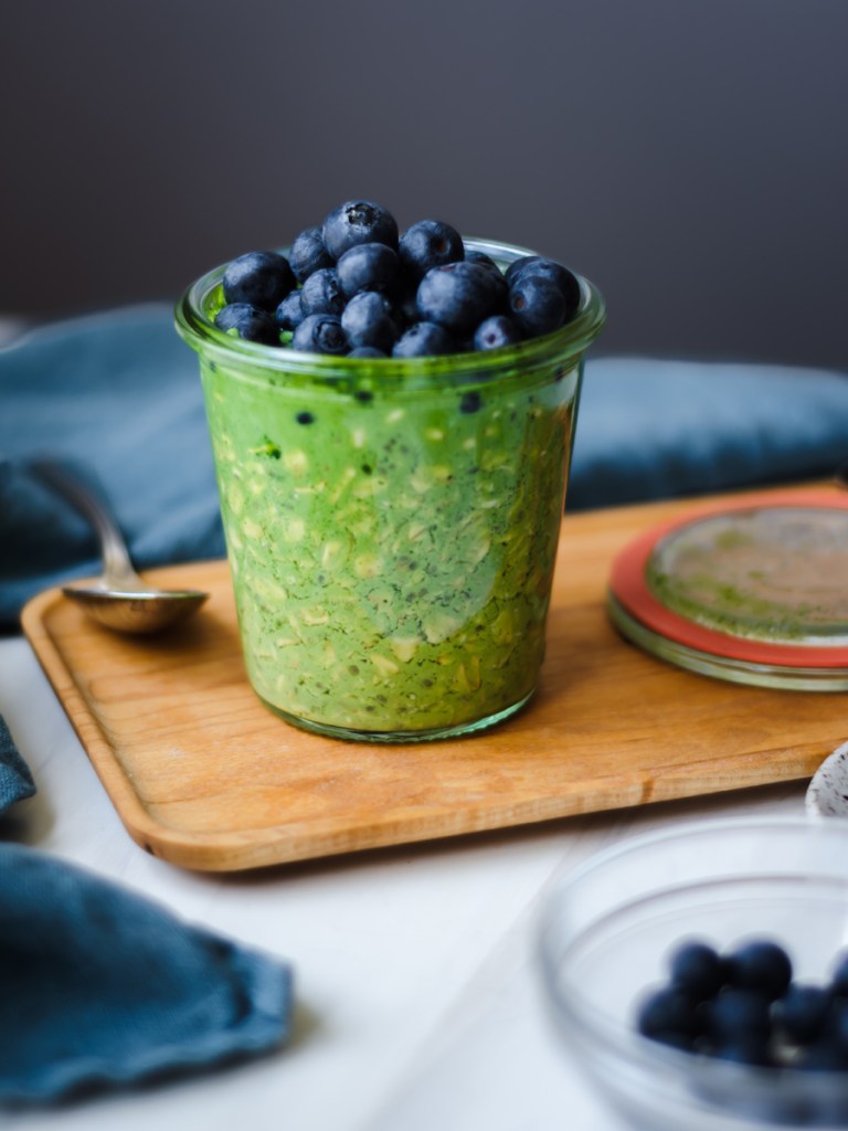 a glass jar with matcha overnight oats and blueberries