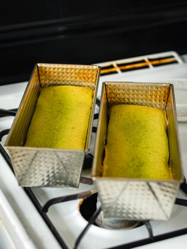 two loaves of freshly baked matcha mochi cakes resting on a stovetop 